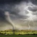 A tornado touches down in a rural landscape under a stormy summer sky with lightning, showcasing a dramatic weather event.