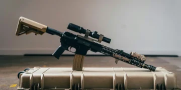 A semi-automatic rifle with a scope is placed on top of a hard plastic case, highlighting the ongoing discussions around bump stocks and potential bans.