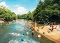 A large crowd of people swim and gather around a natural waterway in Connecticut, surrounded by trees on a sunny June 18-23, 2024, basking in the extreme hot weather.