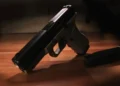 A black handgun lying on a wooden surface next to a detached magazine featured prominently in recent Caribbean crime news.