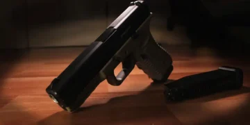 A black handgun lying on a wooden surface next to a detached magazine featured prominently in recent Caribbean crime news.