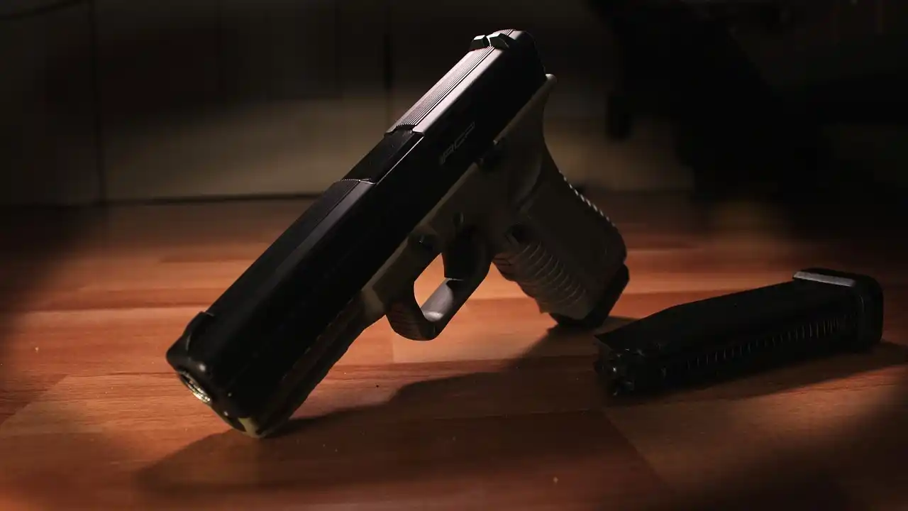A black handgun lying on a wooden surface next to a detached magazine featured prominently in recent Caribbean crime news.