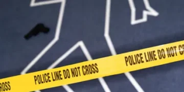 A crime scene with yellow "Police Line Do Not Cross" tape, a chalk outline of a body, and a handgun on the ground marks the site of the Arkansas grocery store shooting, adding to the tragic narrative of gun violence.