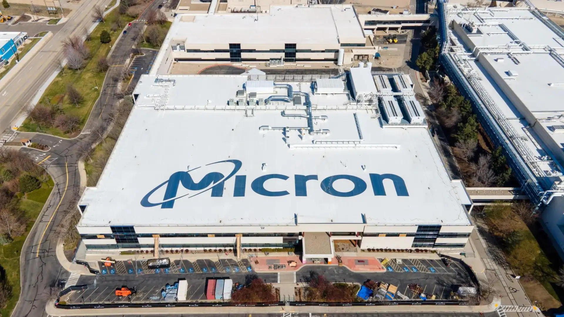 Aerial view of a large industrial building with "Micron" written on the roof, surrounded by parking lots and smaller structures, highlighting the scale of operations central to the Micron earnings report.