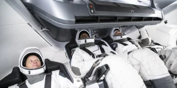 Three astronauts in white spacesuits are seated and secured inside a modern NASA spacecraft, equipped with advanced technology. This deorbit vehicle ensures their safe return from space.