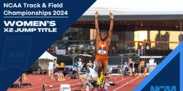 An athlete, Ackelia Smith, in mid-air during a long jump at the NCAA Track & Field Championships 2024, with "Women's X2 Jump Title" text on the image. Stadium and spectators in the background.