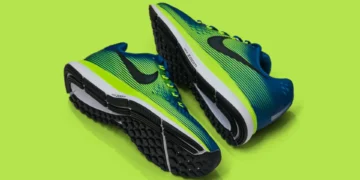 Image of a pair of blue and green athletic running shoes with black soles, placed on a bright green background, showcasing the innovative design that Nike CEO John Donahoe praised for its blend of style and performance.