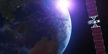 A satellite, part of the Luxembourg-based SES O3b mPOWER network, orbits near Earth with the sun's rays illuminating both the planet and the satellite, casting a vibrant glow on the image.