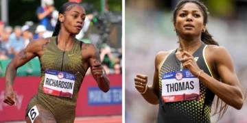 Two female athletes, Sha'Carri Richardson and Gabby Thomas, are running on a track, each wearing bibs with their names. They're fiercely competing in the 200m Olympic Qualification event.