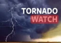 Image of dark storm clouds with lightning, displaying the text "TORNADO WATCH" in bold white and red letters. Issued by NWS, this warning highlights the severe New York weather conditions.