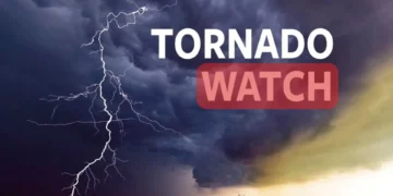 Image of dark storm clouds with lightning, displaying the text "TORNADO WATCH" in bold white and red letters. Issued by NWS, this warning highlights the severe New York weather conditions.