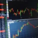 A computer screen displaying multiple stock market charts with fluctuating graphs, numerical data, and columns listing various US stocks and indices, including Nike shares.