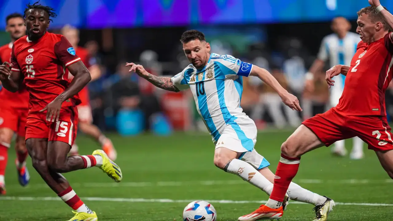 Three soccer players in action: Lionel Messi in a white and blue striped jersey, reminiscent of Lionel Messi in Argentina's Copa America kit, dribbles the ball between two players in red jerseys on a green field.