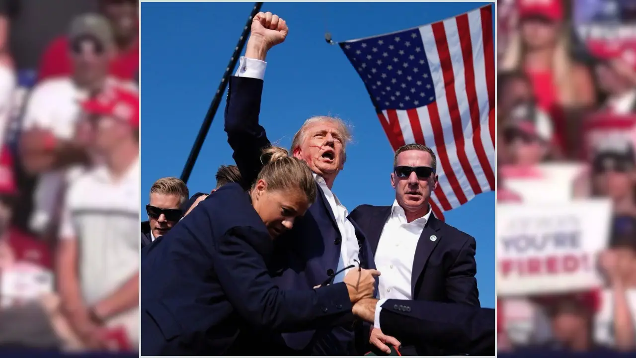 Former President Donald Trump in a suit raises his fist while surrounded by security personnel, with an American flag in the background at a Pennsylvania Rally after alleged assassination attempt featuring Former President Donald Trump.