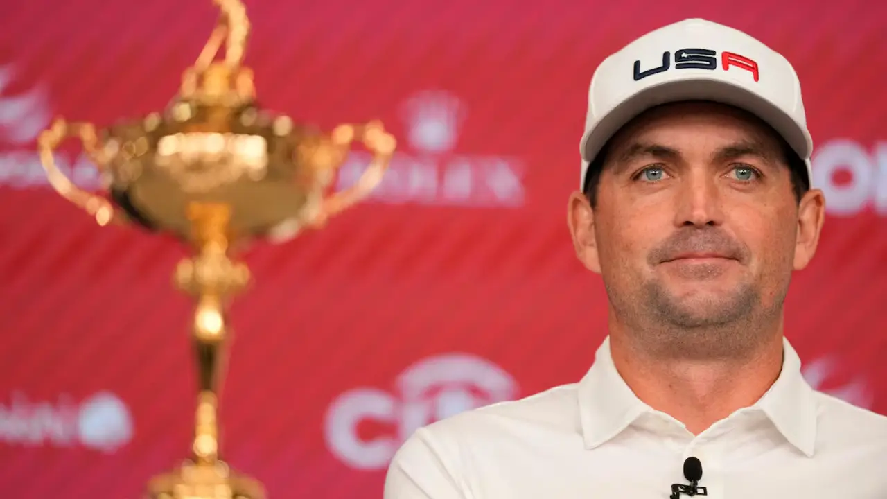 A man in a white shirt and cap, identified as U.S. Ryder Cup Captain Keegan Bradley, stands next to a golden trophy against a red backdrop, possibly celebrating the 2025 event.