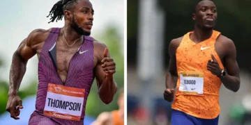 Two male athletes in mid-run, with Kishane Thompson in a purple uniform labeled "Thompson" on the left, and Tebogo in an orange uniform on the right, competing at the Gyulai István Memorial outdoor track event in the Men's 100m race.