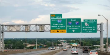 Multiple-lane highway with green overhead signs indicating exits 155B for I-110 North, and 155A for I-10 East towards New Orleans/Hammond, and LA-30 to Nicholson Dr/Highland Rd with cars driving below on a Louisiana highway.