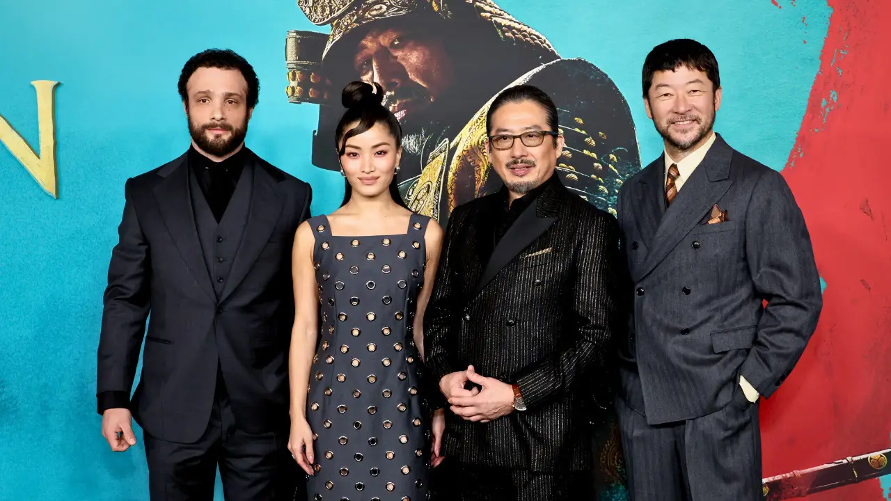 Four FX series Shogun cast members stand side by side in formal attire against a blue backdrop with a large image of a historical figure in the background, celebrating their Emmy nominations for the 2024 Emmys.