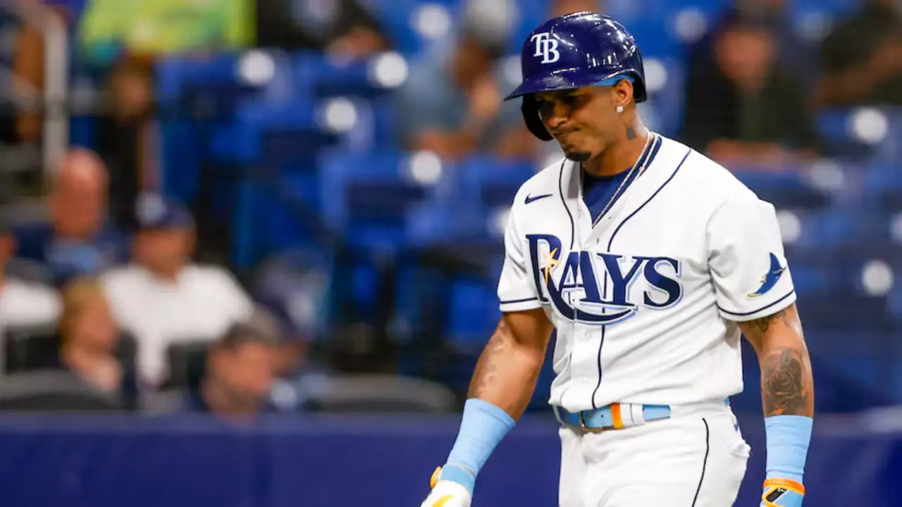 Wander Franco in a Tampa Bay Rays uniform stands on the field. He is holding a bat and wearing a helmet, reminiscent of Wander Franco's stance during crucial moments.