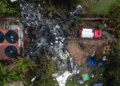 Aerial view of the Vinhedo crash site featuring debris, emergency vehicles, rescue tents, and personnel amidst trees and a building, as covered in aviation accident news.