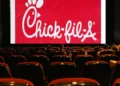 A nearly empty movie theater with a red Chick-fil-A advertisement displayed on the screen offers a nostalgic contrast to the growing trend of entertainment moving towards streaming services.