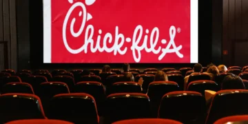 A nearly empty movie theater with a red Chick-fil-A advertisement displayed on the screen offers a nostalgic contrast to the growing trend of entertainment moving towards streaming services.
