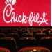 A nearly empty movie theater with a red Chick-fil-A advertisement displayed on the screen offers a nostalgic contrast to the growing trend of entertainment moving towards streaming services.