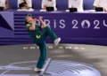 Rachael 'Raygun- Gunn in a green uniform performs a kick during a taekwondo event at the Paris 2024 Olympics, with judges seated at a table in the background.
