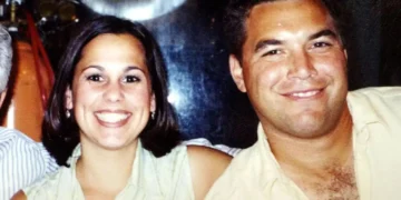 A man and woman smile at the camera while sitting closely together, their expressions masking a tragic past linked to the notorious 2002 murder involving Scott Peterson’s wife and unborn child. The background is slightly blurred.