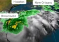 Satellite image showing Hurricane Francine approaching the Gulf Coast with marked locations of Houston, New Orleans, and Brownsville. The storm has green and yellow indicating rain and swirling gray clouds. Evacuation orders have been issued for affected areas.