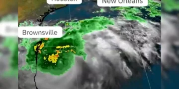 Satellite image showing Hurricane Francine approaching the Gulf Coast with marked locations of Houston, New Orleans, and Brownsville. The storm has green and yellow indicating rain and swirling gray clouds. Evacuation orders have been issued for affected areas.