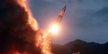 Amidst silhouetted hills, a rocket launches into the evening sky, bright flames and smoke marking its ascent—a scene reminiscent of North Korea's missile testing that often stirs global tensions.