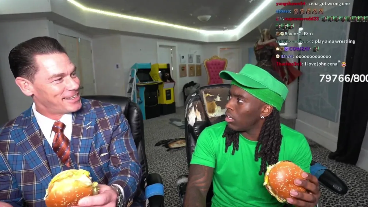 Two people are enjoying Chicken Big Macs while seated at a gaming setup. One is in a suit, the other dressed in green, reminiscent of Kai Cenat's style. Chat messages flash across the screen, adding to the lively atmosphere.