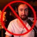 Amidst a backdrop of gaming gear, a figure with headphones and a microphone is crossed out by a red prohibition symbol, signaling Twitch's strict stance on hate speech policy enforcement.