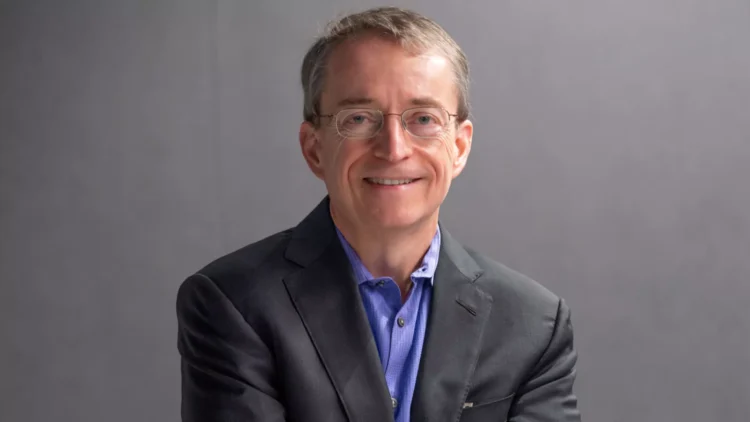 Pat Gelsinger wearing glasses, a dark suit, and a blue shirt smiles confidently against a gray background, embodying the poised demeanor of a CEO from a tech giant.