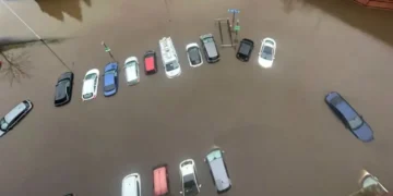 Aerial view of multiple cars partially submerged in floodwater in a parking lot, a result of the torrential rain sweeping through North-West England.